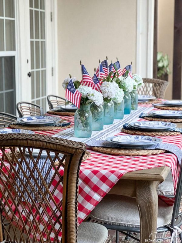 outdoor table with a red and white checked tablecloth and a mason jar table runner with flags and white hydrangeas creative outdoor table decor ideas