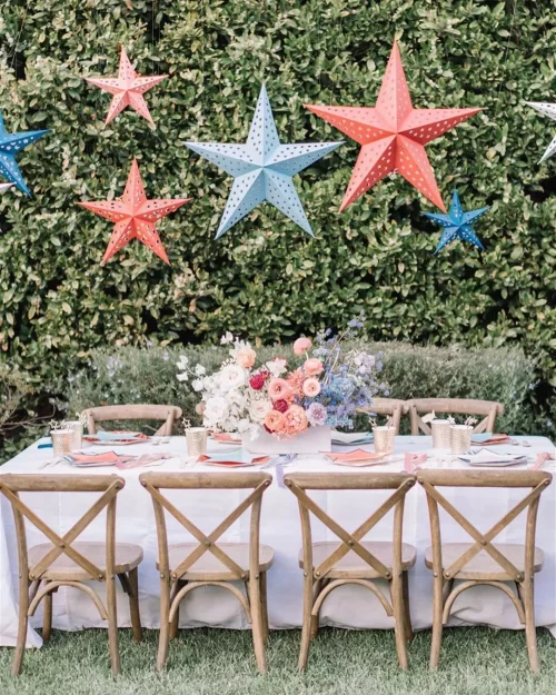 4th-of-july-party-additional-seating-Inspireme2diy A dining table set outside with red and blue stars hanging overhead