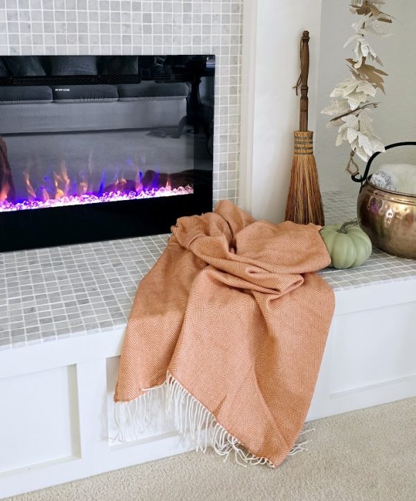 orange blanket on a fireplace hearth decorate for fall when it feels like summer