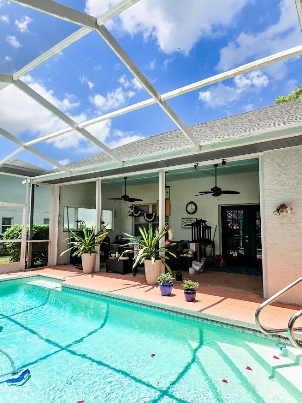 a swimming pool with a covered sitting area and potted plants