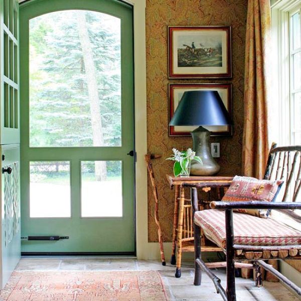 entryway with green screen door, bench and table with lamp