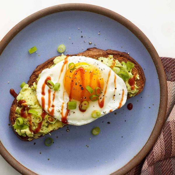 bread on a plate with avocado and a fried egg on top
