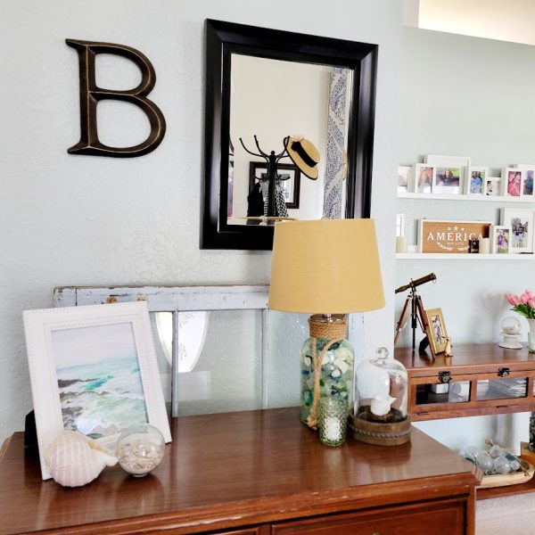 wooden chest of drawers with a lamp and framed art on top and a large mirror on the wall