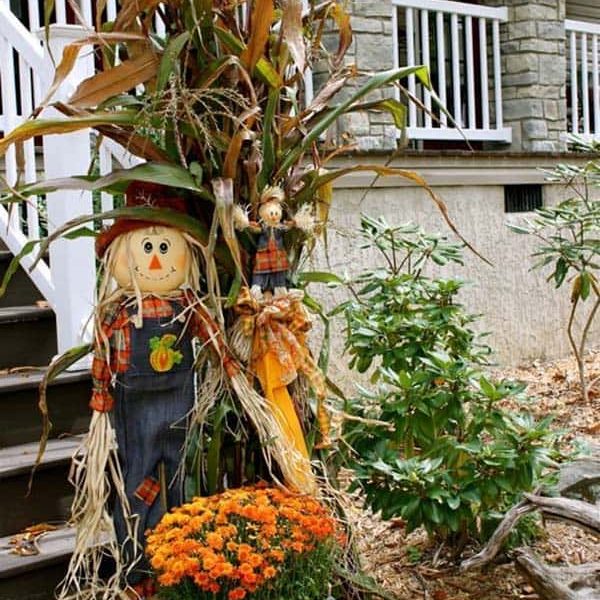 Porch steps with scarecrow, corn stalks and flowers