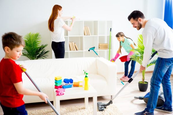 two adults and two children cleaning a living room