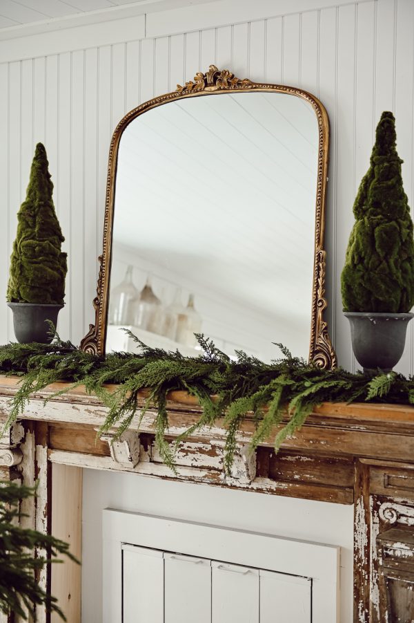 Large mirror on a mantel with greenery