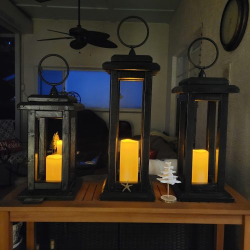 three black lanterns with battery-operated candles decorate for fall when it feels like summer