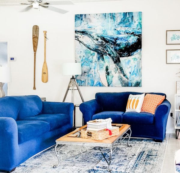 family room with navy sofa and loveseat and a large whale picture on the wall coastal decor ideas for a beach-inspired loo