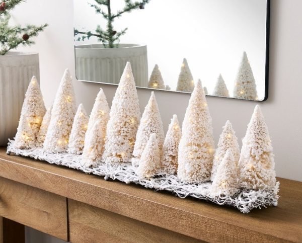 a collection of white bottle brush trees on a table in front of a mirror a beautifully decorated Christmas home