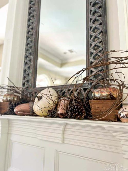 pumpkins and pinecones on a fireplace mantle