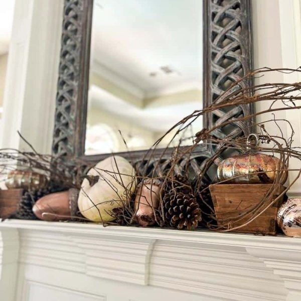 pumpkins and pinecones on a fireplace mantle