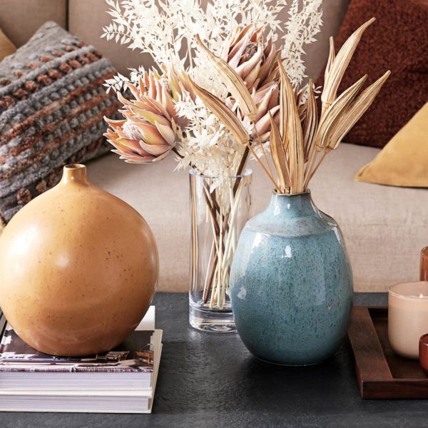 colorful vases on a table with dried plants