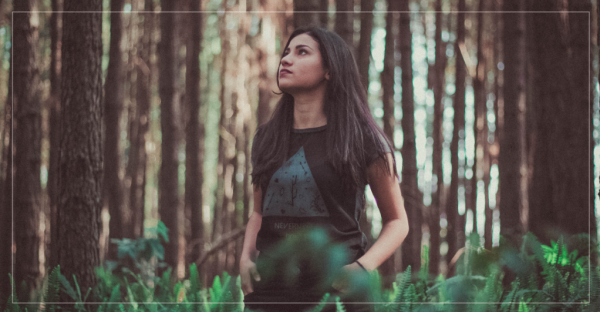 a woman standing in the woods finding peace in God's creation