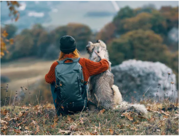 a woman and a dog looking out over a field