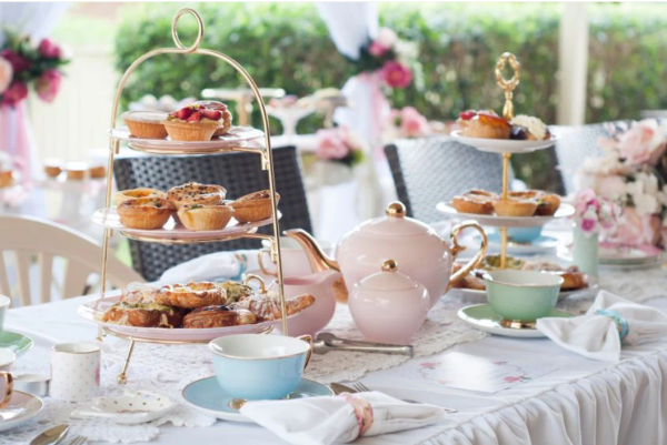 a tea party set up outside with colorful teapots hosting the perfect tea party