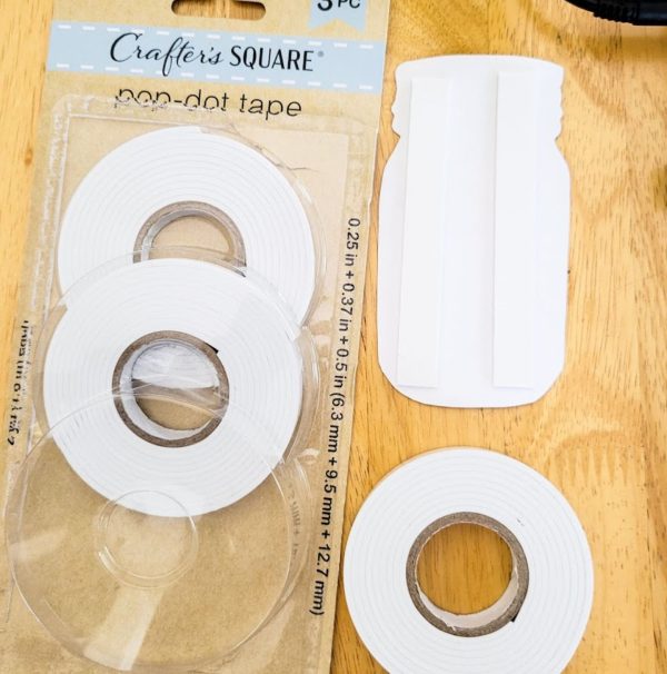a picture of the package of sticky tape and a paper cutout of a Mason jar