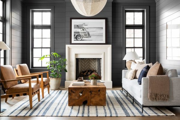 a black living room with a white fireplace and a striped rug