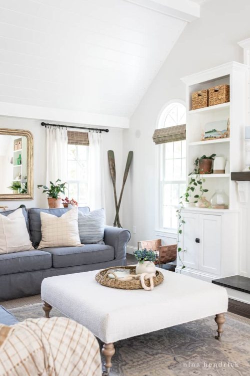 a coastal-inspired living room with high white ceilings and a blue sofa