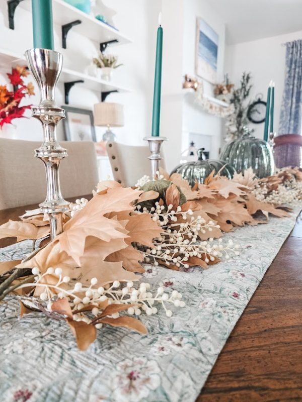 a table with fall florals and silver candlesticks with green candles