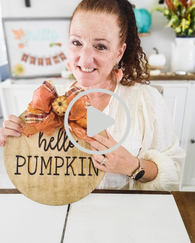 a woman holding a hello pumpkin sign how to DIY your own fall door hangers