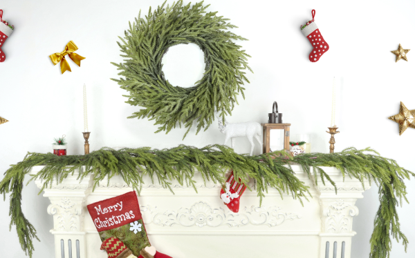 a pine swag on the fireplace and a pine wreath on the wall. a beautifully decorated Christmas home