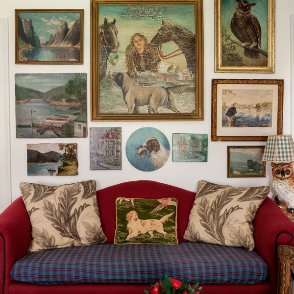 art gallery wall behind a red sofa with pillows