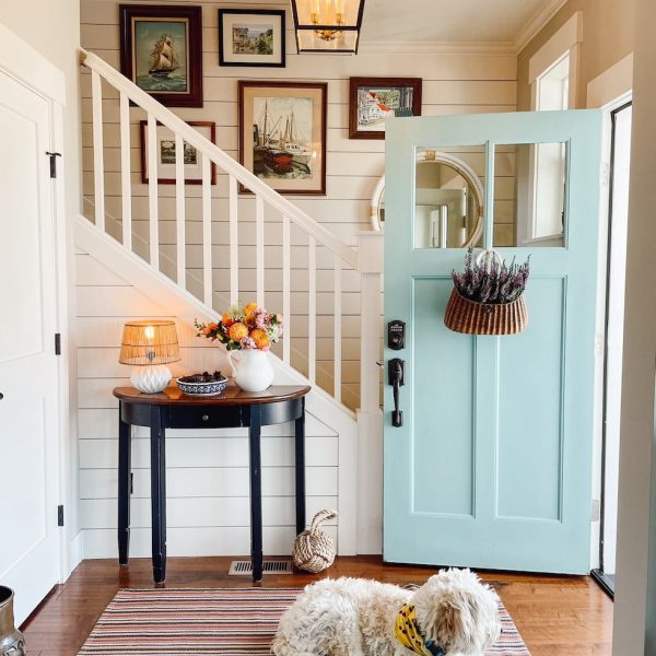 Entryway with large rug, staircase, aqua door and small console table