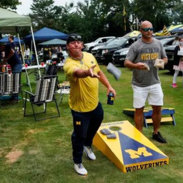 Two men playing cornhole at a tailgate party