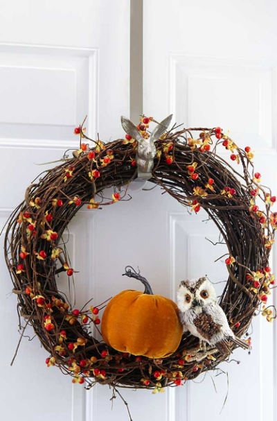 grapevine wreath with bittersweet berries and an orange pumpkin