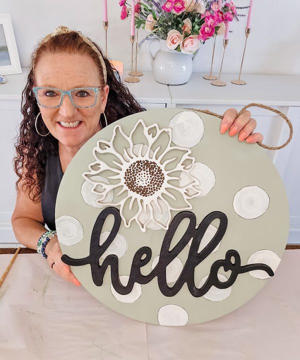 a woman holding a round sign that says hello decorate your porch for winter