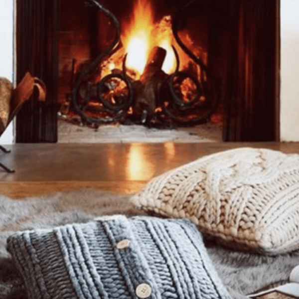 pillows in front of a roaring fire in the fireplace