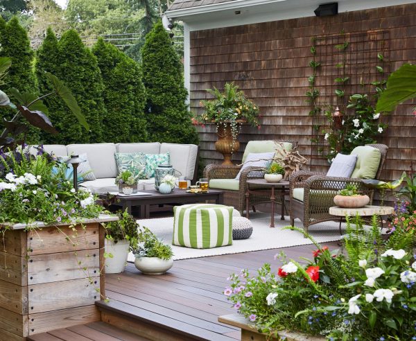 a patio with cushioned furniture, an outdoor rug, and plants patio decor ideas