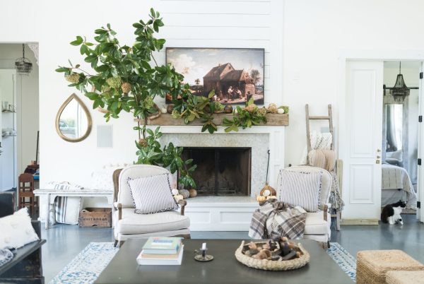 white living room with 2 white chairs and a hardwood floor and a fireplace and plants