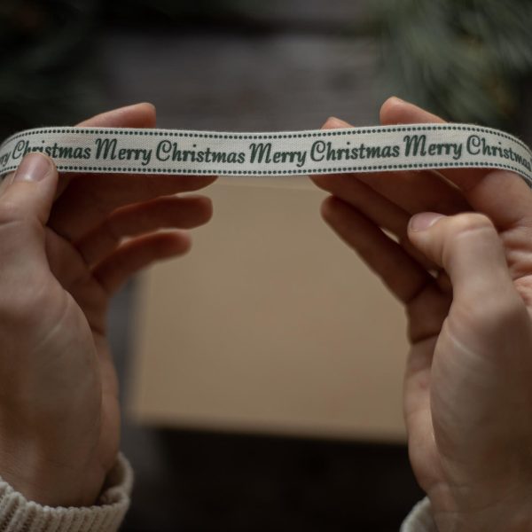 two hands holding a "Merry Christmas" ribbon