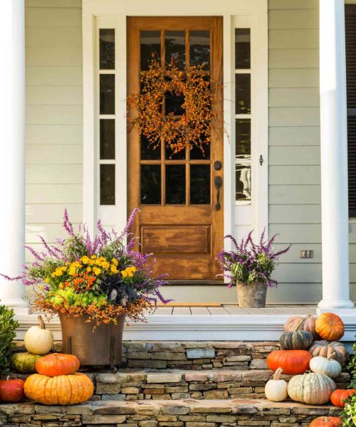 front porch decorated with fall pumpkins and flowers
