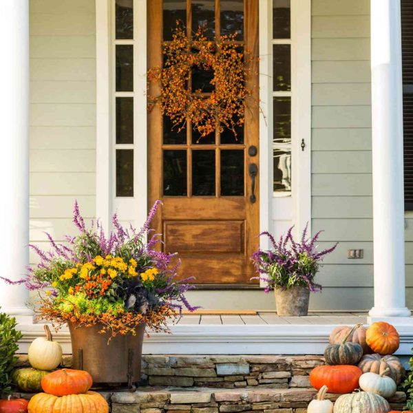 front porch decorated with fall pumpkins and flowers