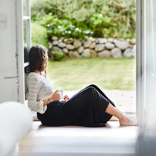 girl sitting in an open window holding hot tea