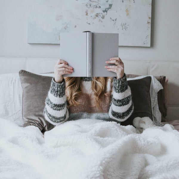 the-theme-of-"home" woman covered up with a blanket reading a book