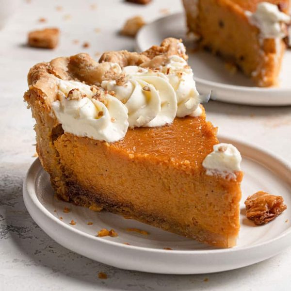 a slice of sweet potato pie with whipped cream on a white plate