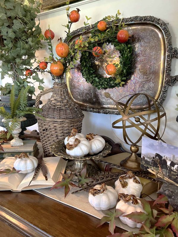 tabletop decor with white pumpkins, an antique tray, oranges, and a woven vase