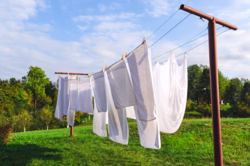 fresh clean white sheet drying on washing line in outdoor how to have a clean home all summer